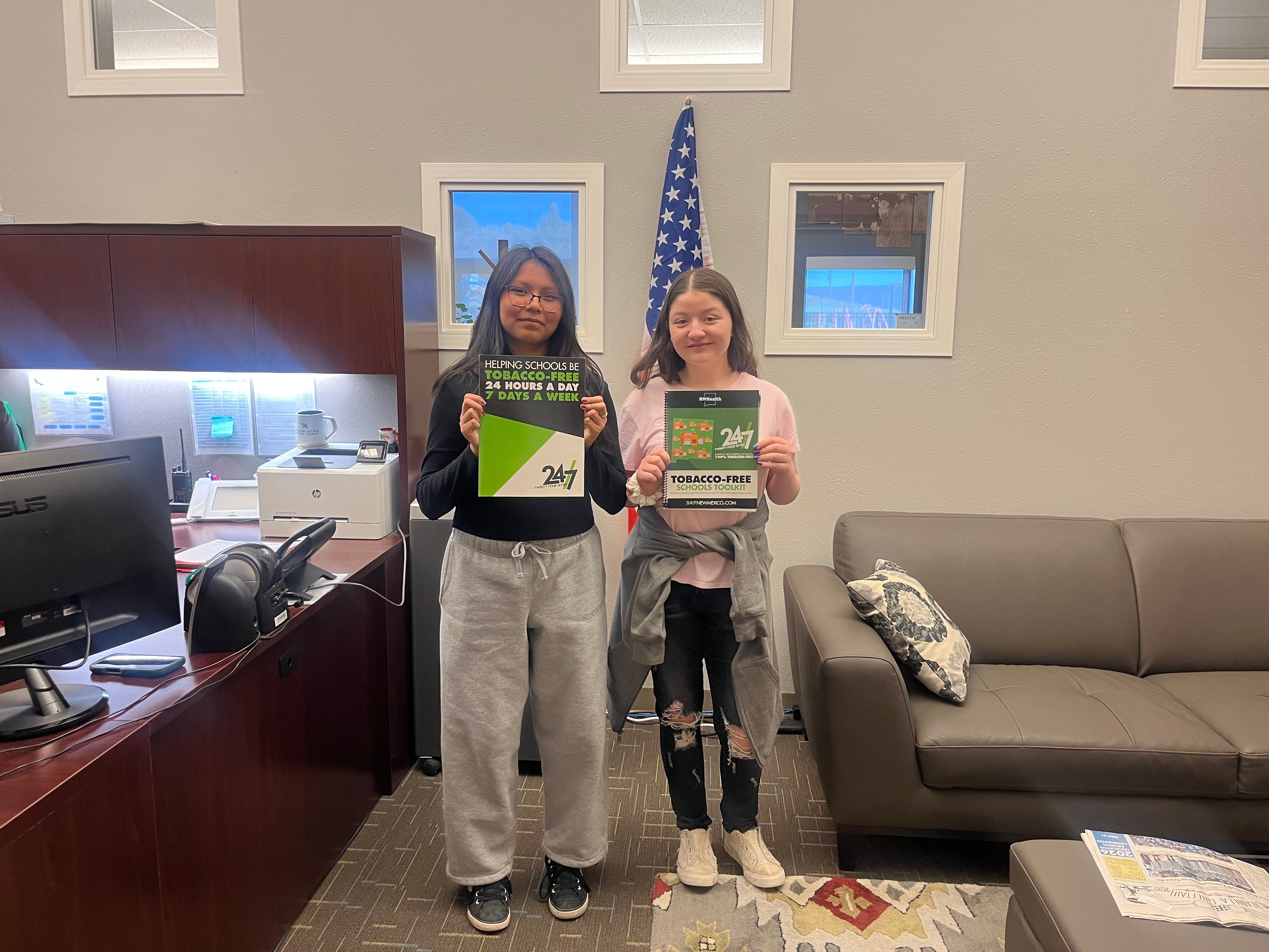 Abigail (right) and Aliliah) left holding up 24/7 resources at their school district office